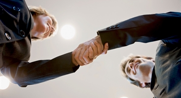 A businesswoman and a businessman shaking hands. The picture is taken from worm´ s eye view.